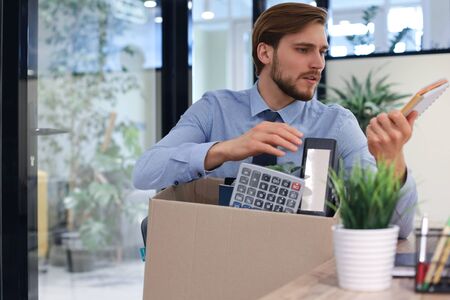 Sad dismissed worker are taking his office supplies with him from office