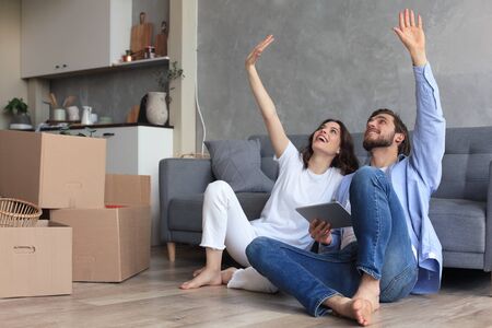Happy couple sitting and planning new home decoration at home with a tablet at moving day, renovation and interior design for new house.の写真素材