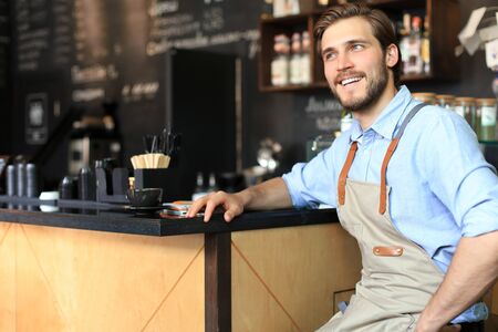 Cafe owner. Pleasant delighted man sitting near the counter, smilingの写真素材