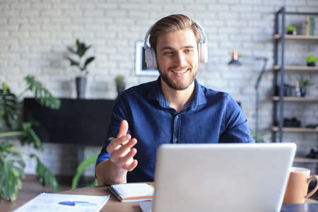 Confident man wearing headset speaking and watching business webinar training, listening to lectureの写真素材