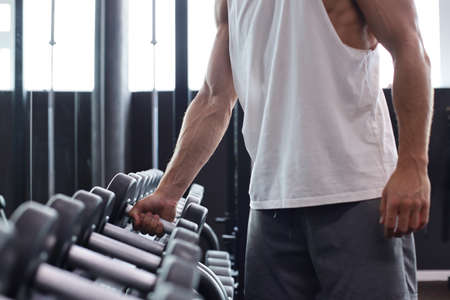 Fitness man in training showing exercises with dumbbells in gymの写真素材