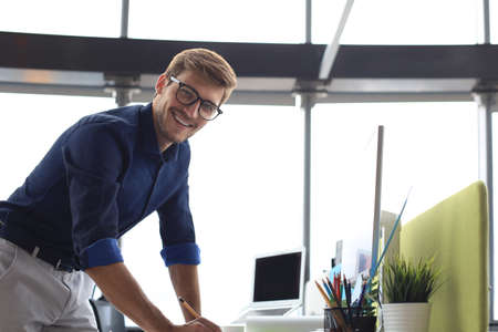 Good looking young business man drawing something while working in the officeの写真素材