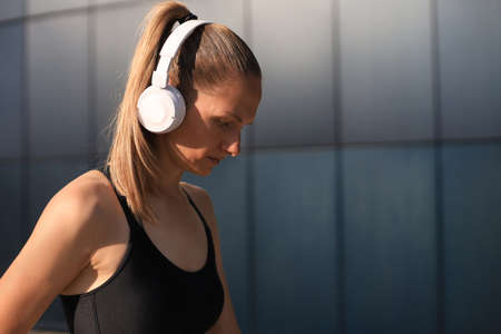 Young fitness attractive sporty girl resting after intensive evening run outdoor at sunset in cityの写真素材