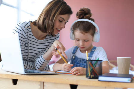Mother and little daughter doing homework online. Distance learning online educationの写真素材