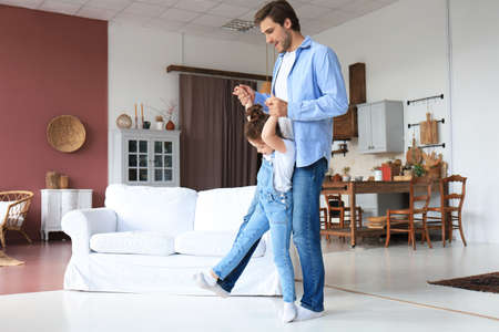 Handsome young man dancing at home with his little cute daugtherの写真素材