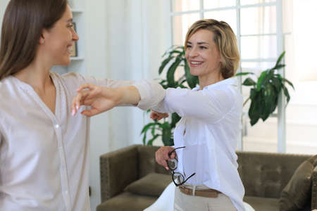 Businesswomen keep their distance because of Covid-19 infection and greet each other with their...