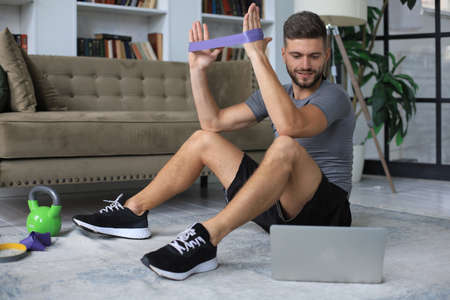 Handsome man doing sport exercise at home during quarantine. Concept of healthy life