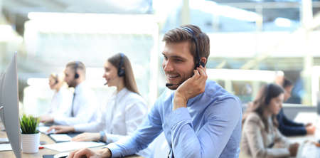 Portrait of call center worker accompanied by his team. Smiling customer support operator at work.の写真素材