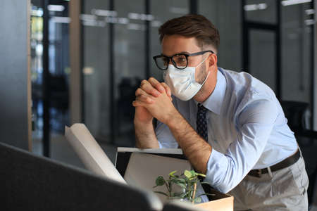 Dismissal employee in an epidemic coronavirus. Sad dismissed worker are taking his office supplies...