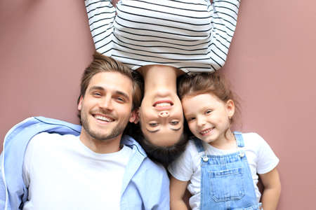 Top view portrait of smiling young parents with little preschooler daughter lying relaxing on warm floor at home, happy family with small child rest have fun at homeの写真素材