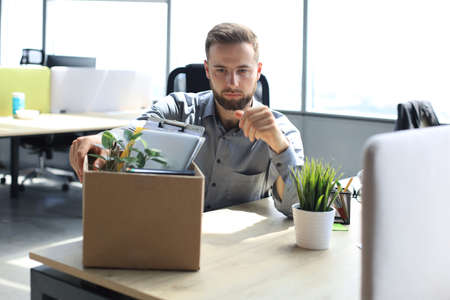 Sad dismissed worker are taking his office supplies with him from office