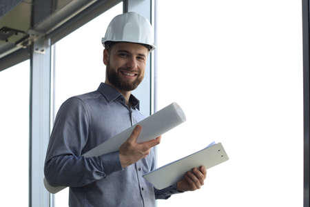 Shot of smiling male architect wearing hardhat and inspecting new building