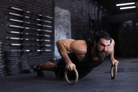 Sporty indian strong man doing push-ups on rings