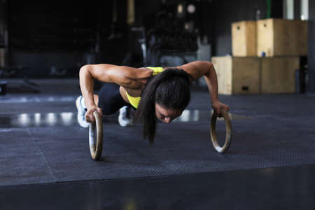 Sporty strong woman doing push-ups on ringsの写真素材