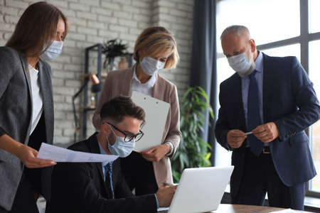 Business people wearing protective face masks while holding a presentation on a meeting during coronavirus epidemicの写真素材