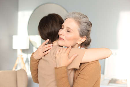 Portrait of old mother and mature daughter hugging at home. Happy trusted relations. Family conceptの写真素材