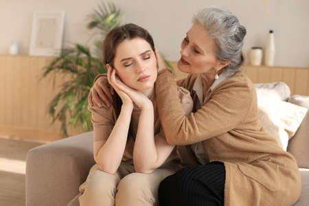 Middle aged mother is embracing her daughter, comforting upset frustrated daughter with closed eyes,...