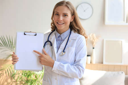 Happy smiling female doctor in white uniform coat and stethoscope