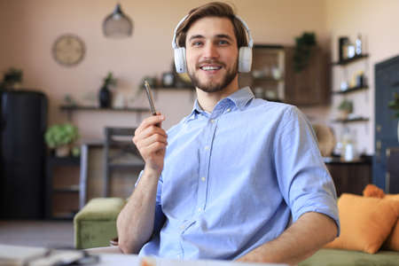 Happy young man in earphones working from home during self isolation