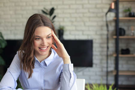 Smiling pretty woman sitting at table, looking at laptop screen. Happy entrepreneur reading message...