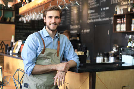 Shot of happy young bar owner standing near the counter and looking at camera, smilingの写真素材