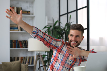 Handsome businessman is keeping arms raised and expressing joyful at home officeの写真素材