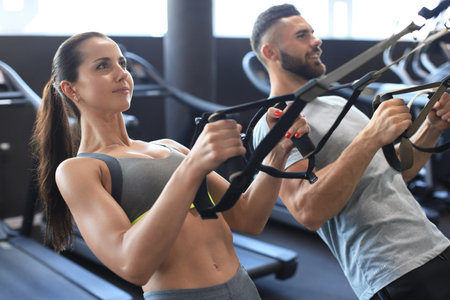 Young couple on body training with trx in gym
