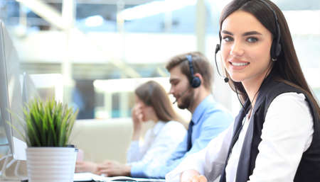 Smiling female call center operator doing her job with a headset while looking at camera