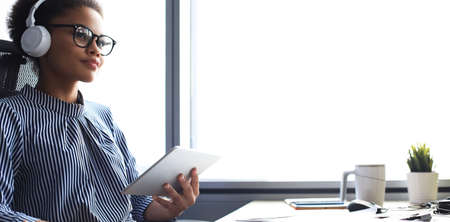 Beautiful african american woman is working using digital tablet while sitting in creative office