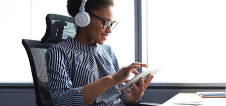 Beautiful business woman is working using digital tablet while sitting in creative office.の写真素材