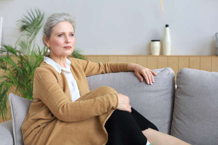 Attractive middle aged woman relaxing in sofa at homeの写真素材