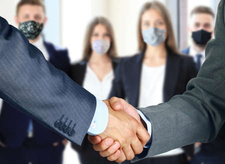 Business people in protective masks shaking hands, finishing up a meetingの写真素材