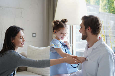 Little girl at the doctor for a checkup. The child auscultate the heartbeat of doctor woman for fun.