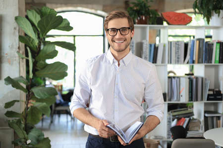 Handsome young businessman standing in modern office