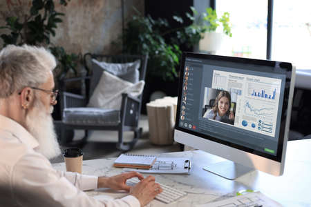 Businessman speak talk on video call with colleagues on online briefing during self isolation and...
