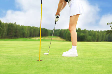 Golf player at the putting green hitting ball into a holeの写真素材