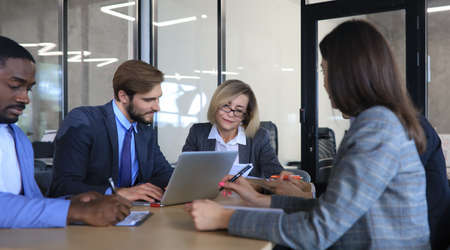Five business people during a meeting sitting around a table