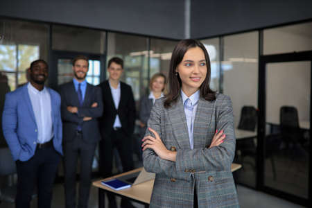 Business woman with her staff, people group in background at modern bright office indoors
