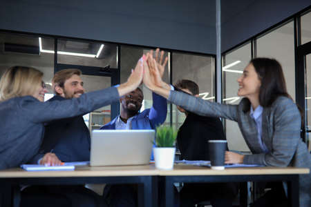Happy people sitting in office and giving high five to their colleaguesの写真素材