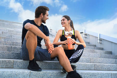 Young couple in sportswear sitting on the stairs after exercising outdoorsの写真素材