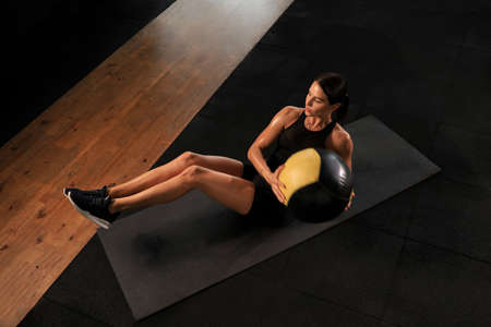 Fit and muscular woman exercising with medicine ball at gym