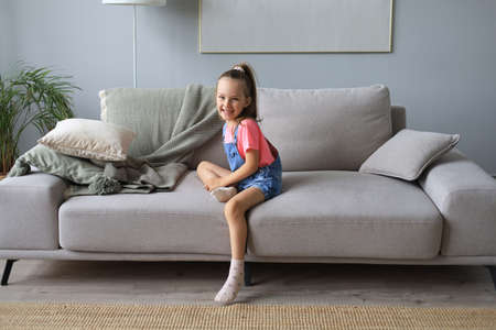 Excited child looking at camera while sitting in living room at homeの写真素材