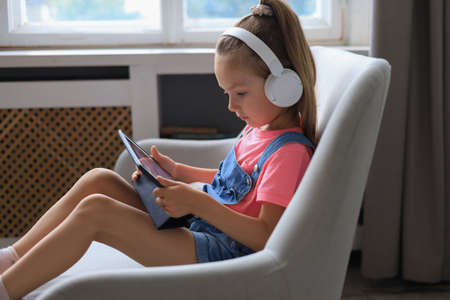 Distance learning. Cheerful little girl using laptop computer studying through online e-learning systemの写真素材
