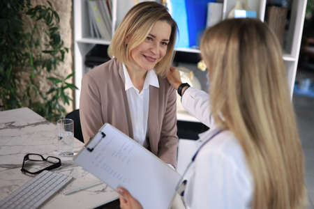 Friendly middle aged female doctor encouraging, supporting patient after medical examination.の写真素材