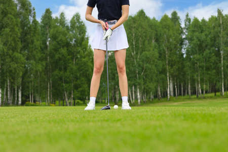 Beautiful woman golfer prepare to shot on ball on the green golf courseの写真素材