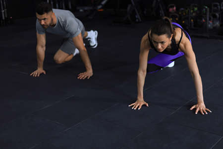 Portrait of beautiful young sports couple on a plank position