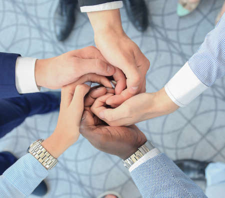 Multiethnic group of young people putting their hands on top of each other. Close up image of young business people making a stack of hands.の写真素材