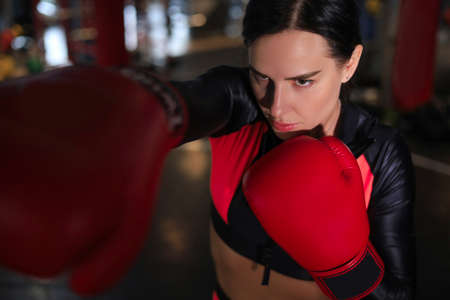 Young sports woman in tracksuit and putting hands together in red boxing glovesの写真素材