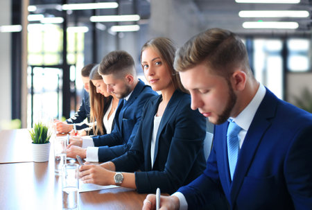 Smiling businesswoman looking at camera at seminar with her colleagues near by.