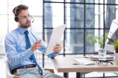 Young man is working with papers while sitting in the office. Successful entrepreneur is studying...